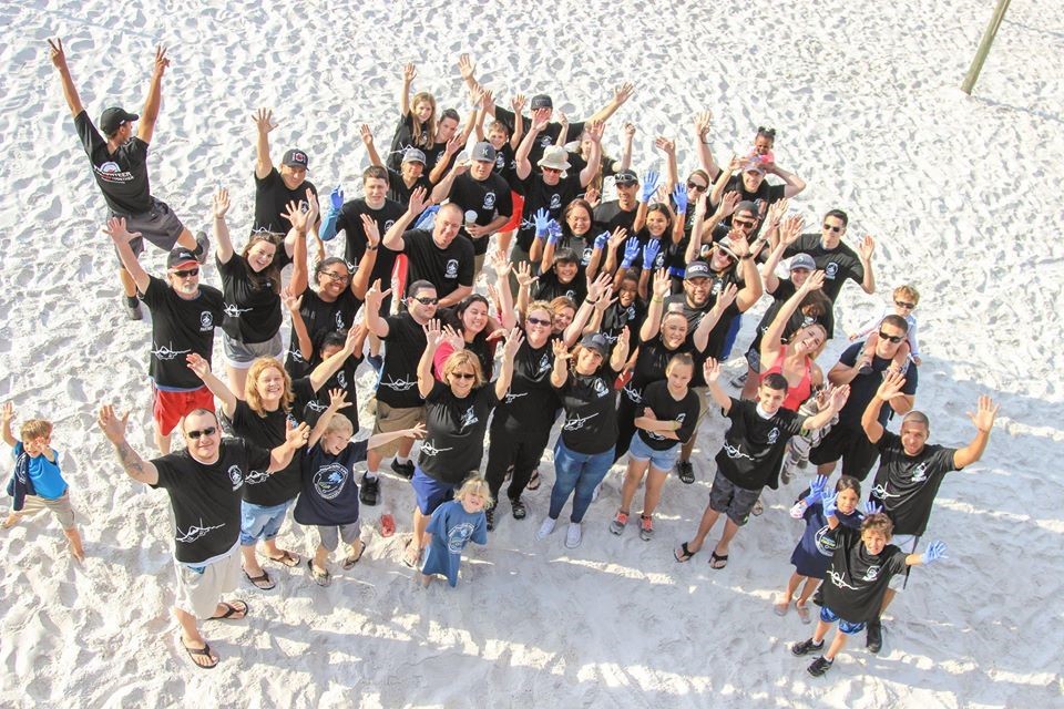 Volunteers celebrate a clean beach as they raise their hands to the pier at Tybee Island beach at a previous year’s cleanup.